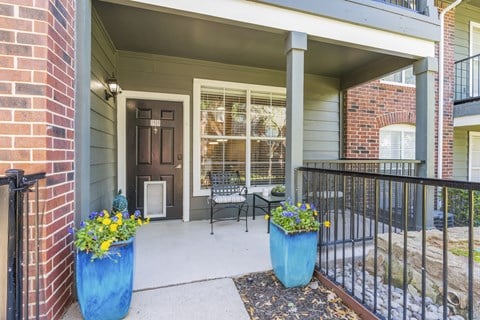 the front porch of a home with two blue vases and a bench